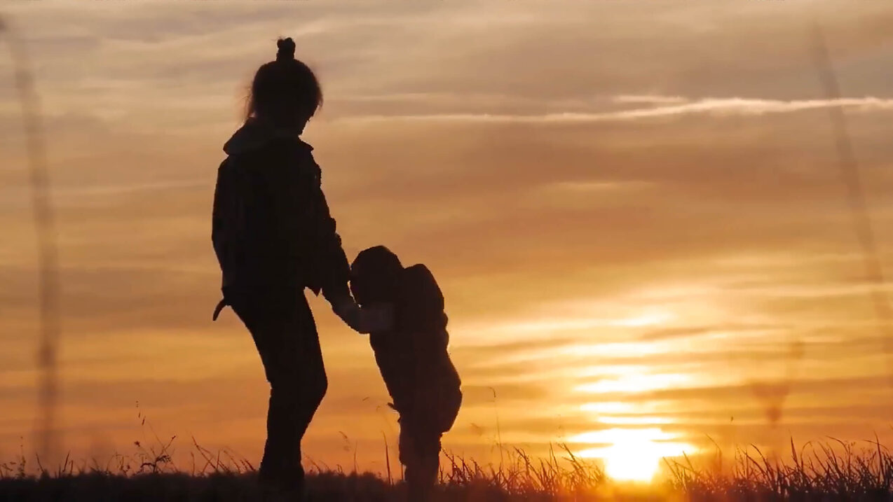 Silhouette of two children holding hands at sunset