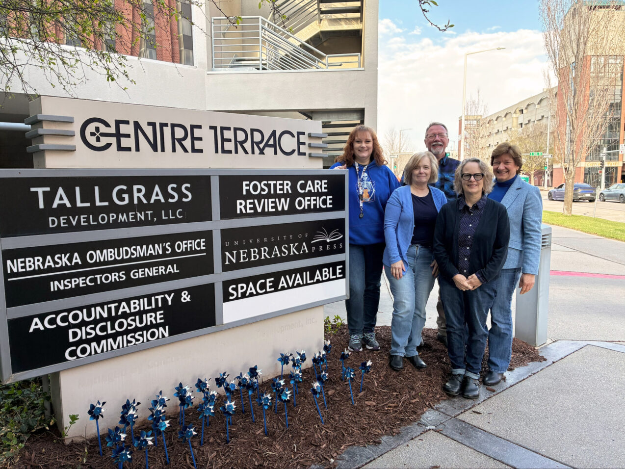 Team members standing outside the Foster Care Review Office building sign in Nebraska